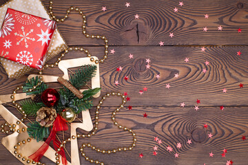 Metallic golden fir tree with branches and cones, Christmas decorations, beads and gifts wrapped in paper on a wooden table. Flat lay, copy space.