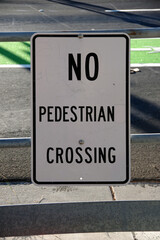 NO PEDESTRIAN CROSSING sign on a barrier along railroad tracks