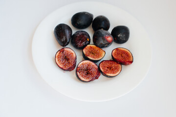 Ripe and sweet figs cut and arranged in a plate on a white background with free space. Fruits and vegetarianism