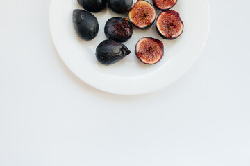 Ripe and sweet figs cut and arranged in a plate on a white background with free space. Fruits and vegetarianism