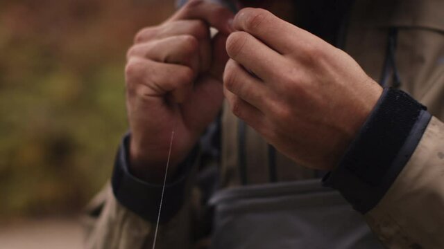 Close up shot of man fly fishing, putting a fly on a hook