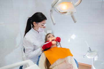 A professional dentist treats and examines the oral cavity of a pregnant girl in a modern dental office. Dentistry