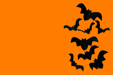 Halloween concept, black paper bats on an orange background. High quality photo