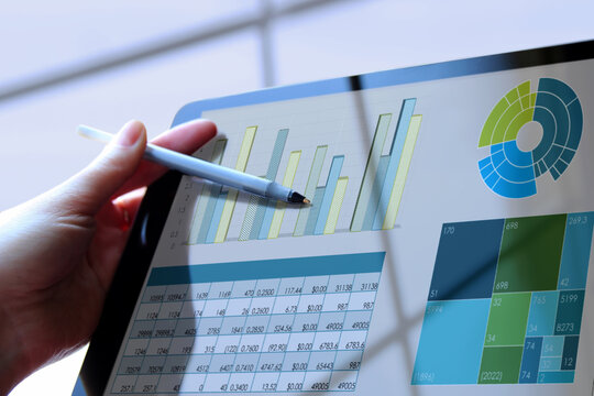 Business woman working and analyzing financial figures on a graphs on a tablet