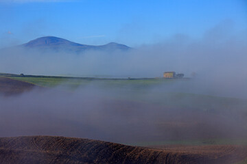 Misty landscape at sunrise in Val d'Orcia, near San Quirico d'Orcia, Tuscany, Italy