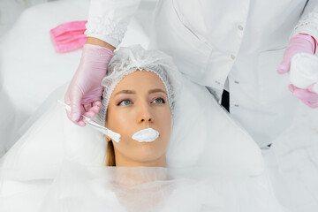 Moisturizing the lips during a cosmetic procedure for a young girl. Cosmetology