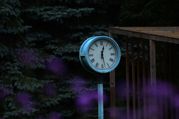 Street round clock with Roman numerals shows 28 minutes of the first.