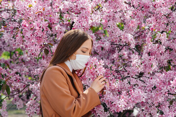 A young girl takes off her mask and breathes deeply after the end of the pandemic on a Sunny spring...