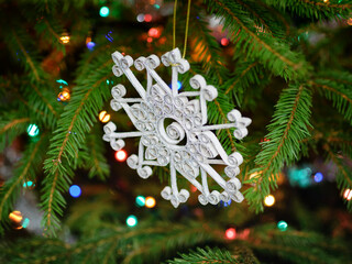 Glitter quilled snowflake - handmade Christmas ornament hanging on a spruce branch