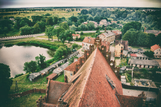 Scenic view of a small town, a pond and a tile church roof, former West Prussia, old photo stylization