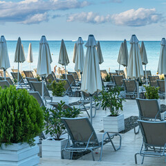 wooden ground on a pebble beach with sun loungers and umbrellas on the Black Sea coast in the resort town of Sochi, Russia