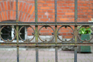 an old metal shaped fence against the background of a red brick building. side view