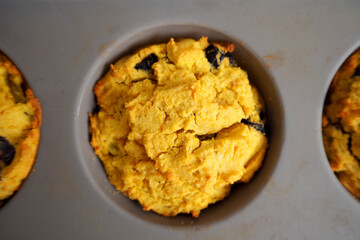 A gluten-free pumpkin cupcake sprinkled with pumpkin seeds lies with a gray silicone mold. top view