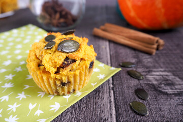 gluten-free pumpkin muffins, sprinkled with pumpkin seeds, lie on a wooden table next to the pumpkin. side view. vegan 