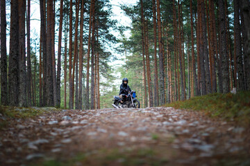 a woman on a motorcycle in nature. motorcyclist walk through the forest