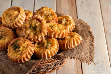 Basket with fresh muffins on wooden background. Homemade cakes with vegetables and cheese. Recipe for autumn seasonal dish.