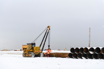 Large tube on loader. Tractor. Construction Marine offshore works. Dam building, crane, barge, dredger.