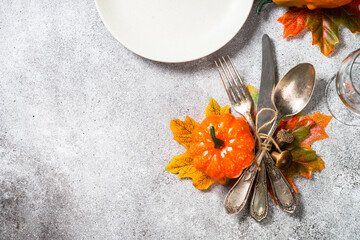 Thanksgiving food background. Autumn table setting with white plate, silverware and fall decorations at stone table. Top view with copy space.
