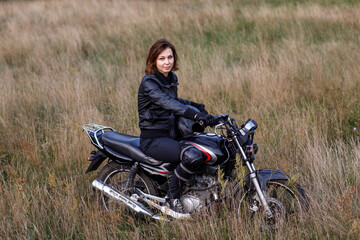 Fototapeta na wymiar a woman on a motorcycle in nature. motorcyclist walk through the forest