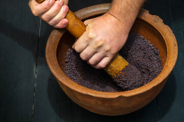 Grinding poppy seeds in an old clay pot for making kutya or pies. The national dish is prepared before any holiday