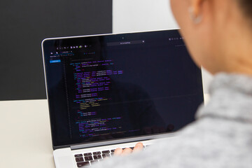 A programmer coding on a laptop in the workplace