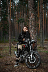Plakat a woman on a motorcycle in nature. motorcyclist walk through the forest