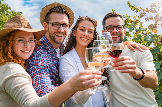 Happy friends having fun drinking wine at winery vineyard - Friendship concept with young people enjoying harvest time together