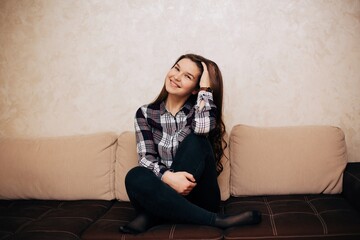 Girl in a cardigan shirt sitting on the couch. Long haired brunette sitting on the couch at home