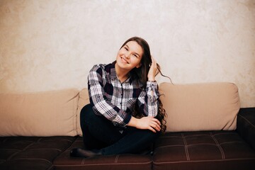 Girl in a cardigan shirt sitting on the couch. Long haired brunette sitting on the couch at home