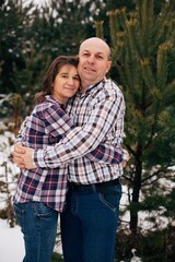 Husband and wife in checkered shirts hugging. Family in the winter forest