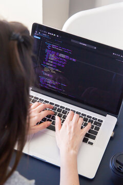 A programmer coding on a laptop in the workplace
