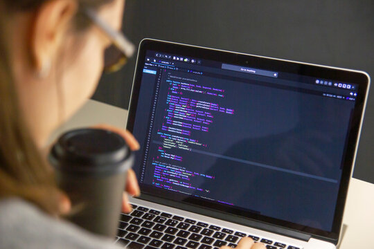 A programmer coding on a laptop in the workplace