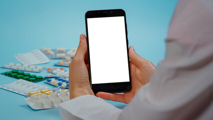 Nurse hand in white coat Use phone with Chroma Key Display for Medication Information. Smarthphone with Mockup, Green Screen Medical. Pills blisters.