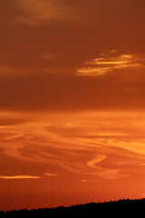 Orange sunset with flowing clouds and mountain range