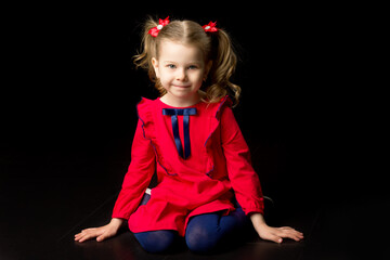Adorable little girl in red dress sitting on floor