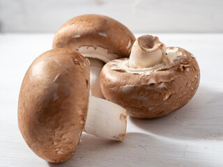 Champignon mushrooms on a white wooden background.