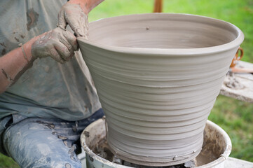 Hands of a man making a clay vase on a potter's wheel