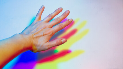 A blurred background with a shadow from the palm of the hand of yellow, red, blue color from three multi-colored light sources