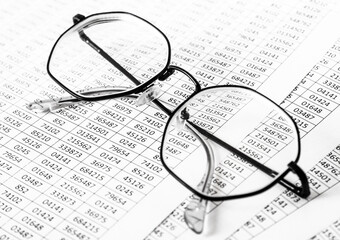 Worksheets or reports showing figures through eye glasses. closeup glasses on financial report. Accounting. financial data. Concept of Business and Finance research .