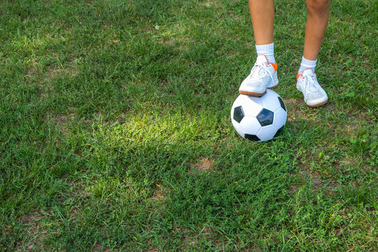 Boy teen puts his leg on ball on soccer field.