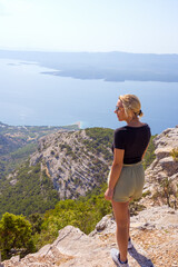 Naklejka premium A girl stands on the edge of a cliff and looks into the distance. 