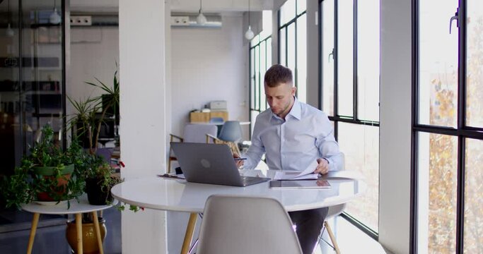 RED camera video of Caucasian confident boss in formal clothing checking paper analytics during working process on modern netbook technology, successful male employee analyzing contract details
