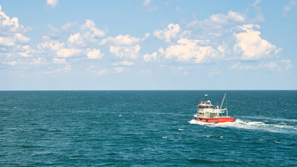 Fototapeta premium Istanbul, Turkey - August 2021: Fishing boat sailing in open waters, distant in seascape.