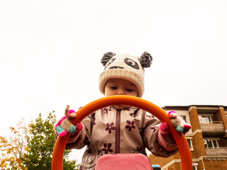 cute and funny baby playing on the playground on an autumn day