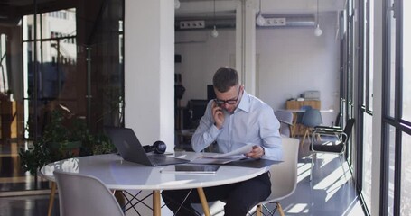 RED camera video of formally dressed male entrepreneur in protection glasses communicate with business partner discussing documents and trade, Caucasian man analyzing banking deals while phoning
