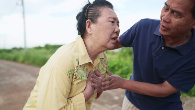 Asian elderly woman having a acute painful in chest caused by heart attack with a worried husband supporting beside, emergency situation, old people and physical disease condition, life insurance