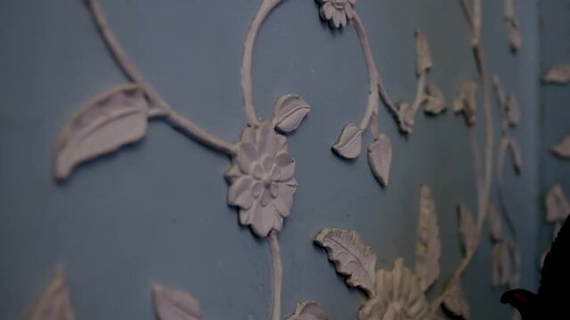 white flower stucco on a blue wall