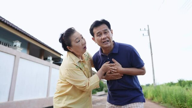 Portrait shot on elderly man holding hand on breast touch chest having heart attack feels unwell with worried wife supporting, acute myocardial infarction symptoms, health problems medical insurance