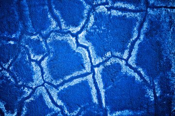 Blue painted wall, cracks in plaster and white random paths.