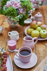 Summer garden background. Bouquet of flowers hydrangeas and  cup of tea on table. Good cozy morning. Picnic in nature. Mother's day greeting card. Celebration